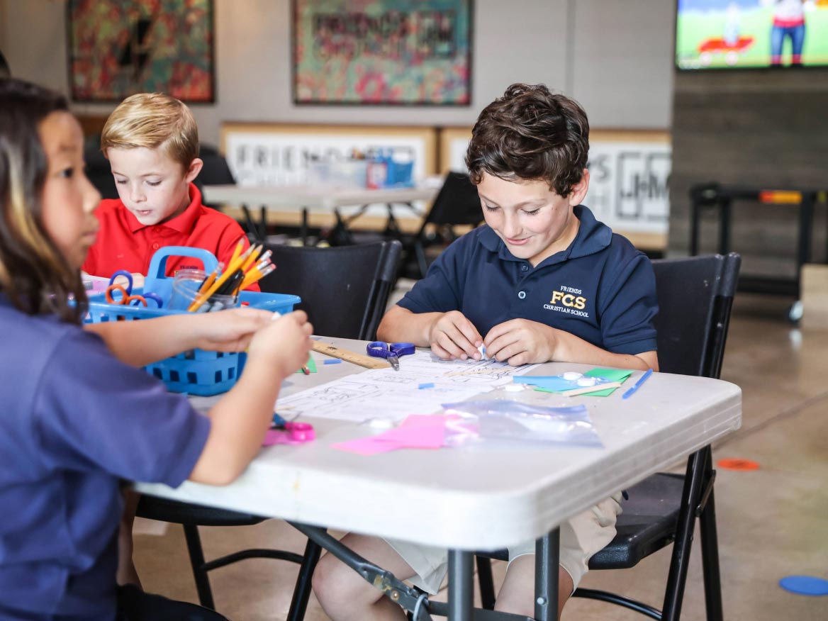 Students working on a hands-on craft project together at a classroom table