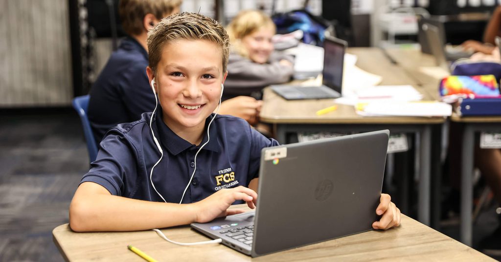 Smiling student wearing headphones while working on a laptop