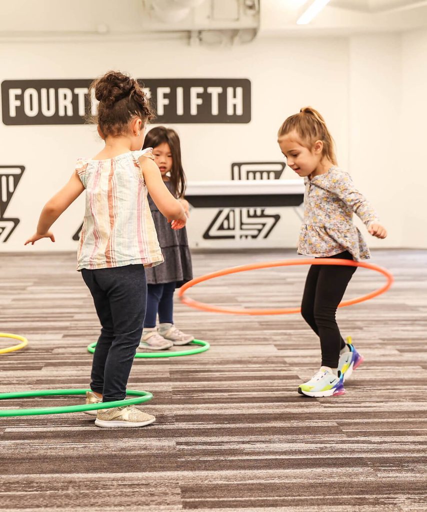 Young students playing with hula hoops during a PE class