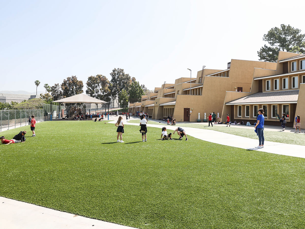 Students playing on the grass field in front of the school buildings