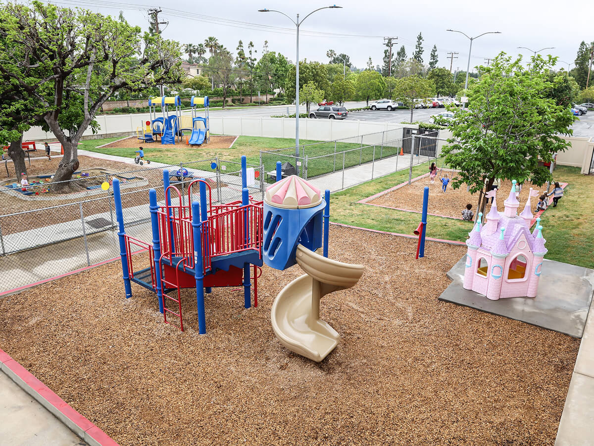 Preschool playground with a slide, climbing structure and playhouse