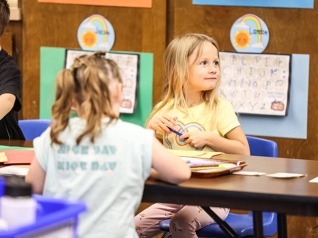 Two young girls working together at a classroom table