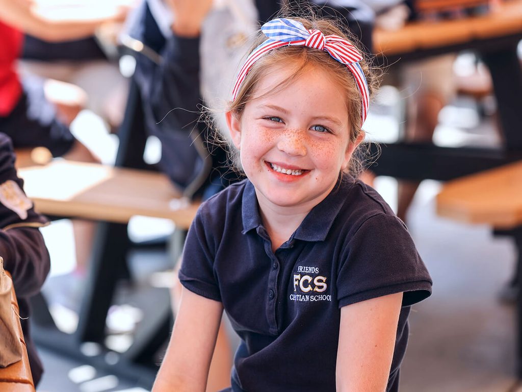 Smiling young girl in a navy FCS uniform shirt in the classroom