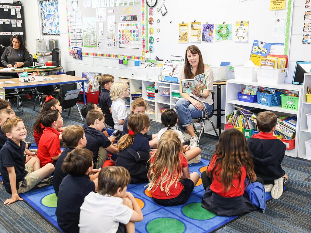 Kindergarten class sitting on the rug while the teacher reads a story