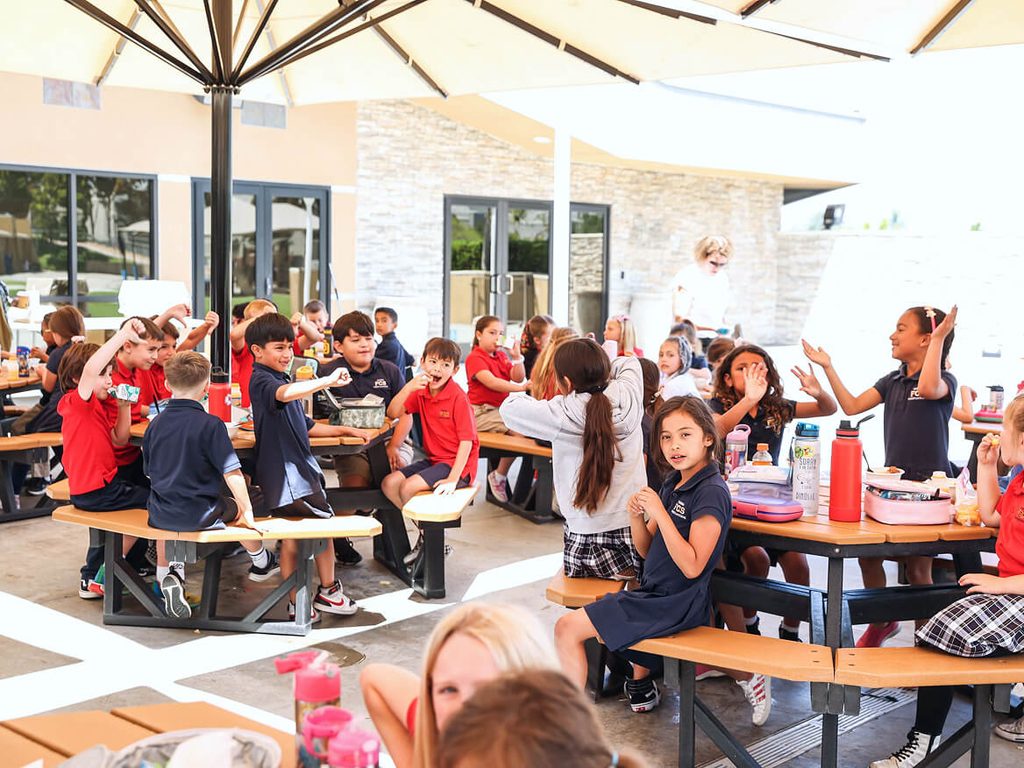 Students eating lunch together at outdoor tables on campus