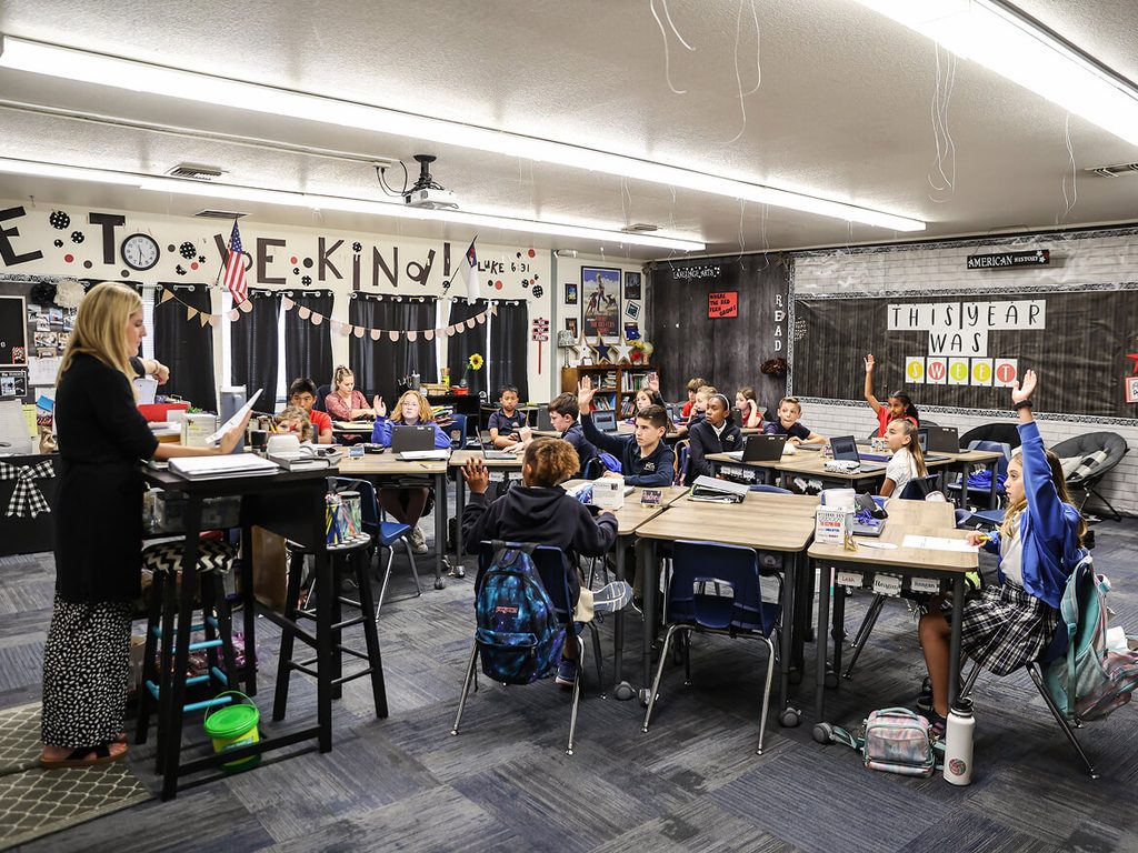 Students working in groups around tables in a large classroom