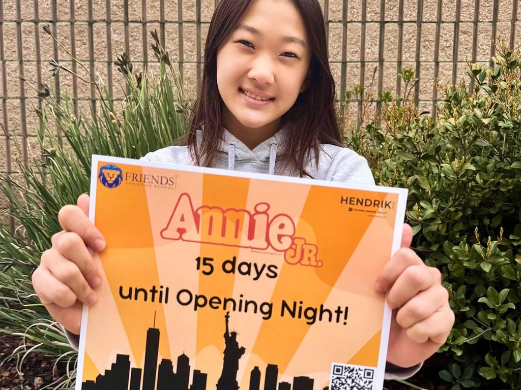 Smiling student holding an Annie Jr. sign counting down 15 days until opening night
