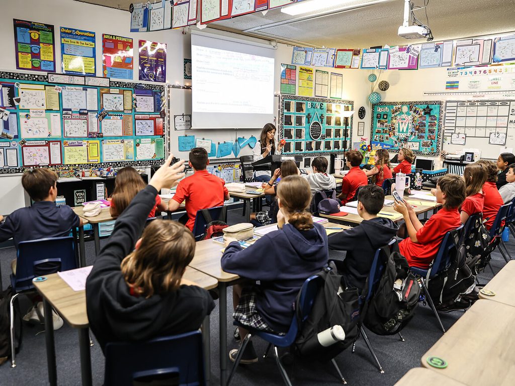 Students working at their desks in a bright, busy classroom