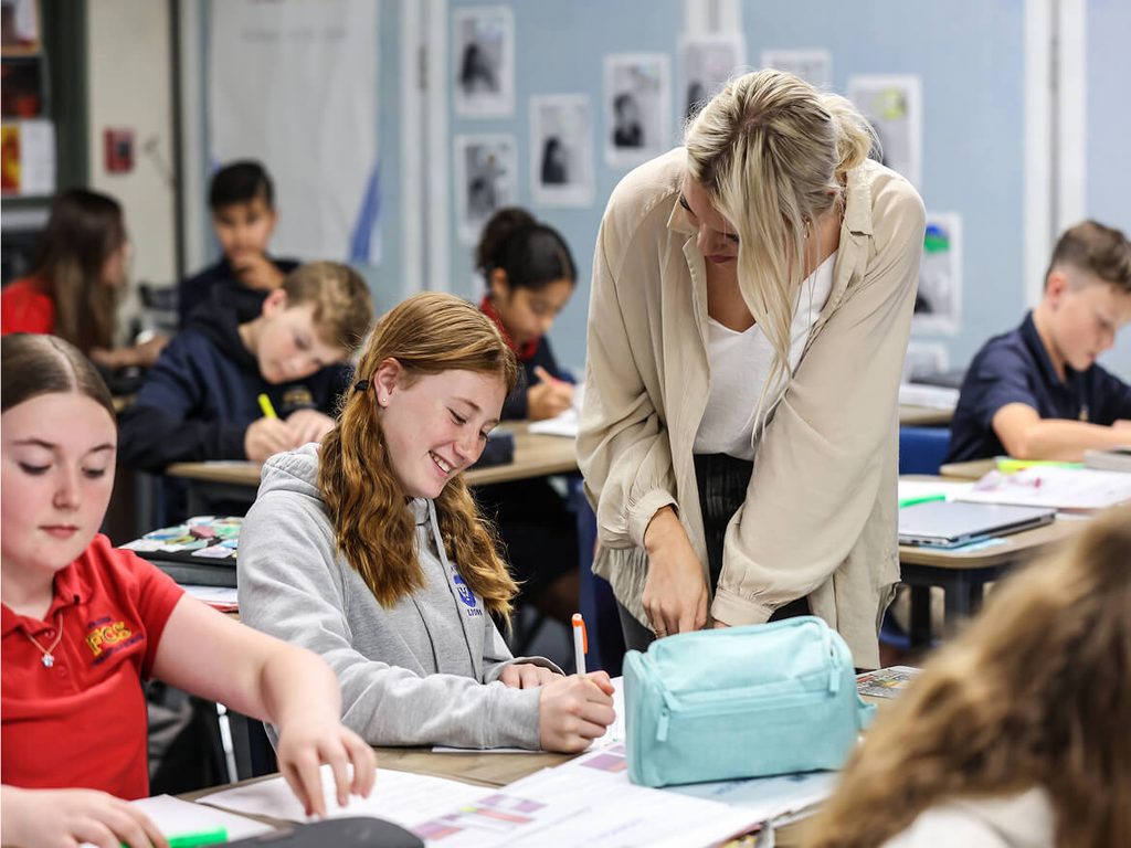 Teacher helping middle school students with their work in class