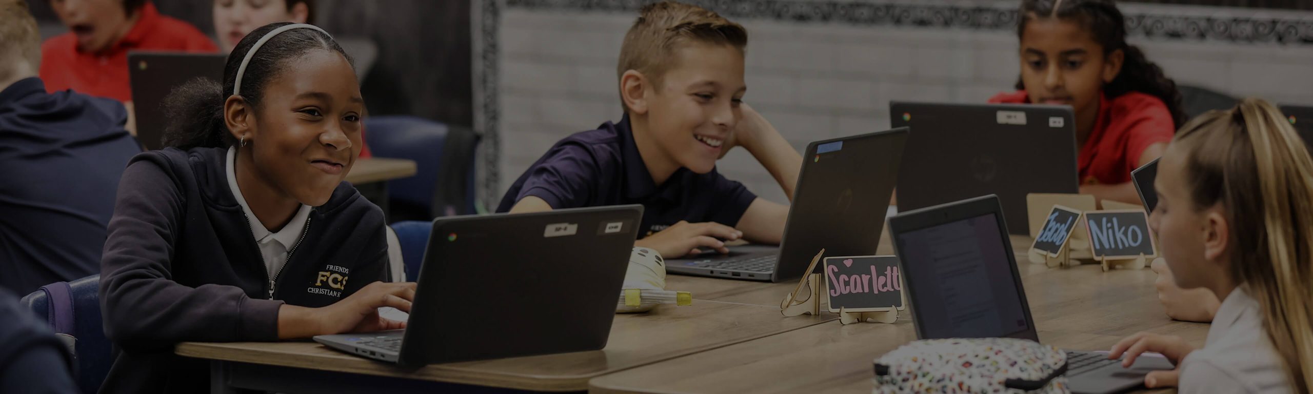 Middle school students working on laptops together in class