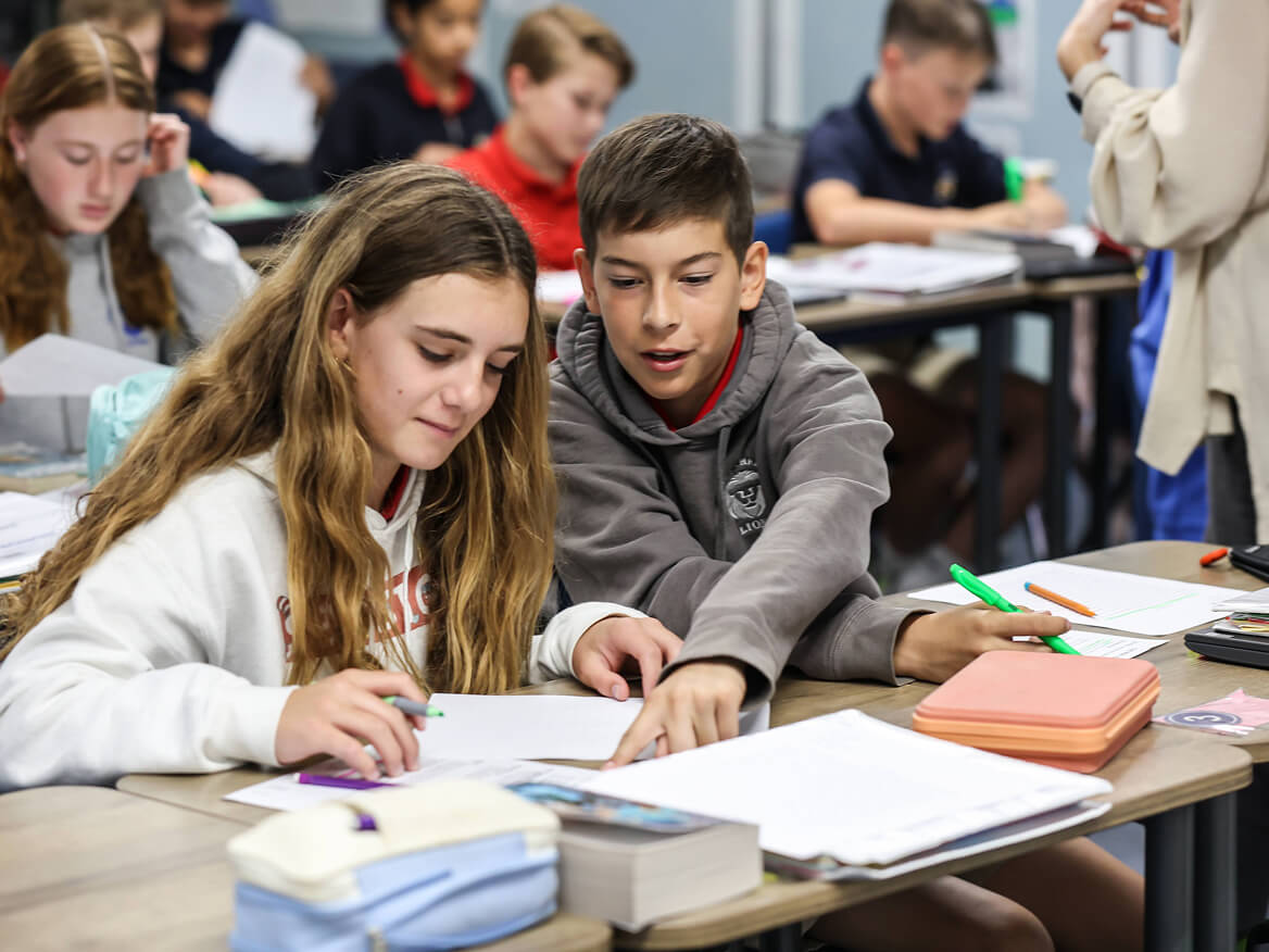 Middle school students working on assignments together at their desks