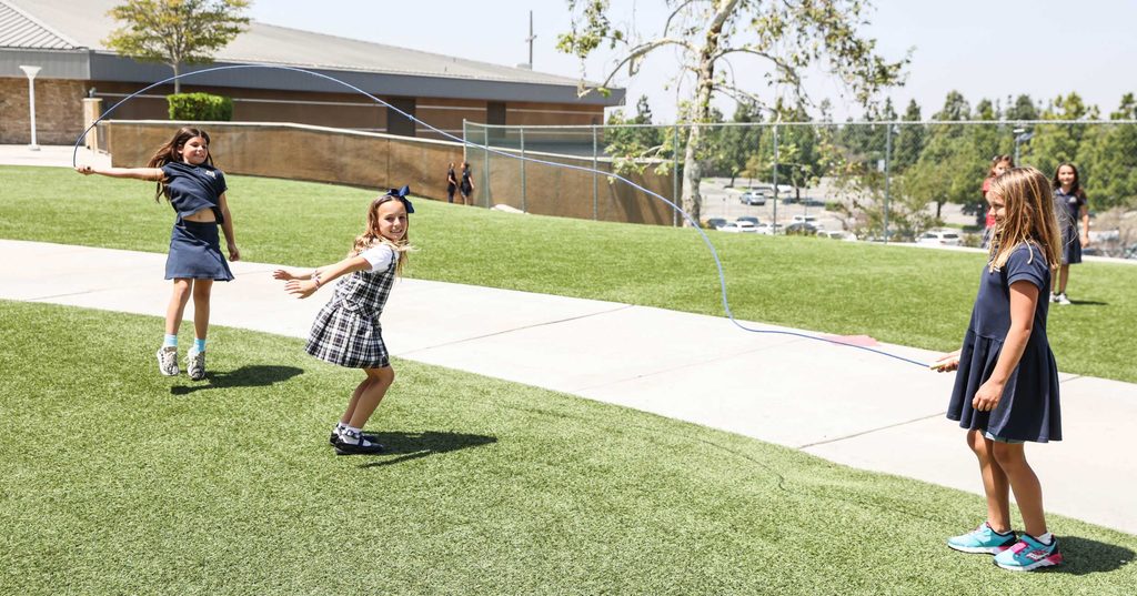 Students in uniforms playing on the grass field on campus