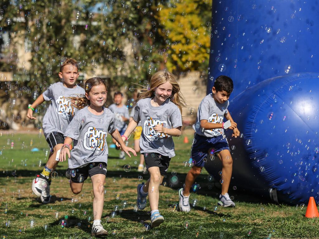 Students in matching shirts running across the field during a school fun run