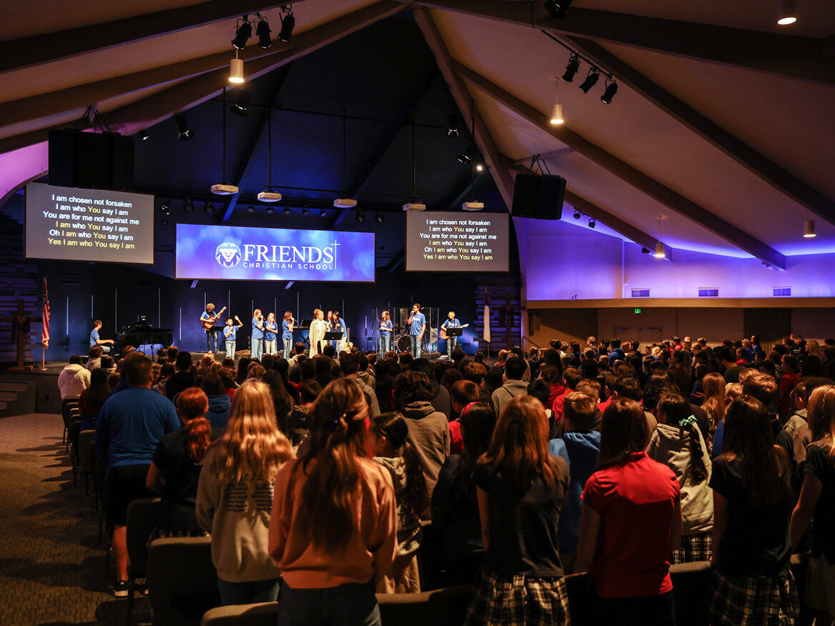 Students and families gathered in a church auditorium for a school worship event