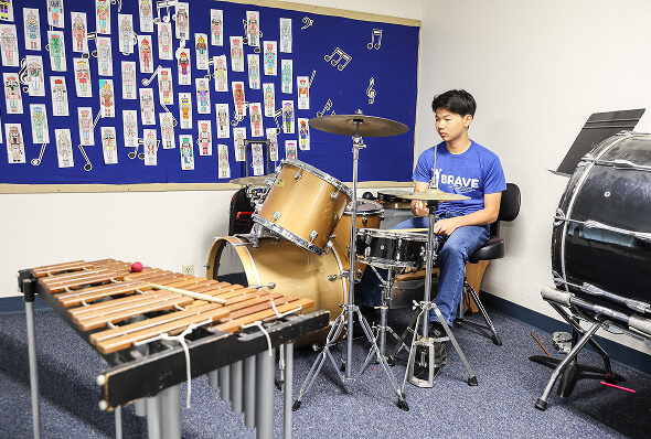 Middle school student playing the drum set in the school music room
