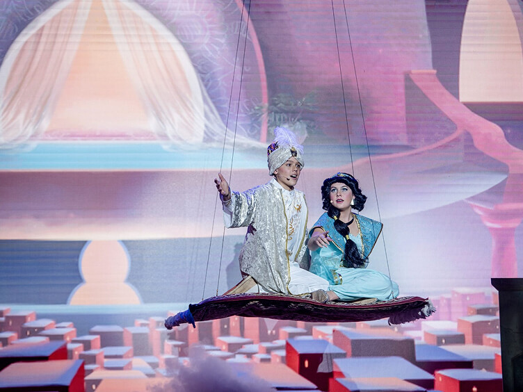 Student actors riding a flying carpet during a musical theater performance