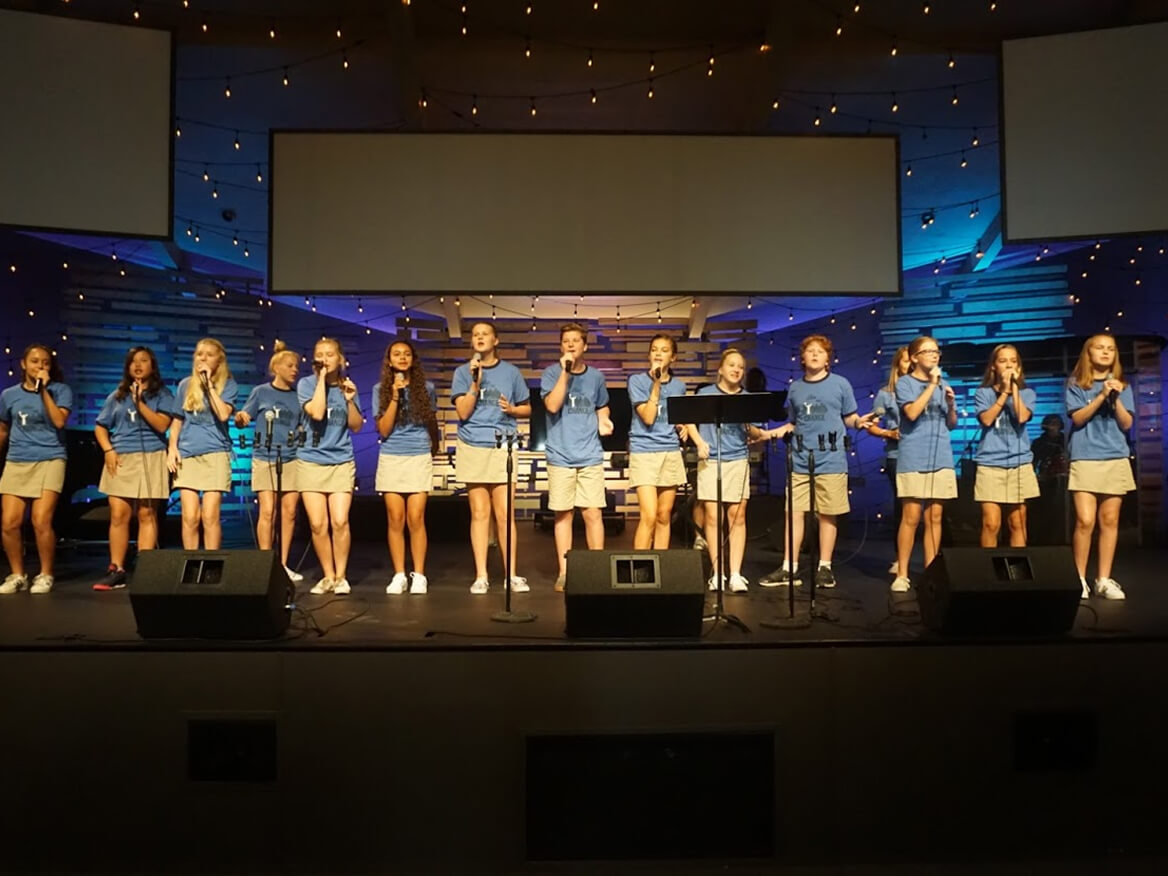 Students in matching blue outfits performing together on stage