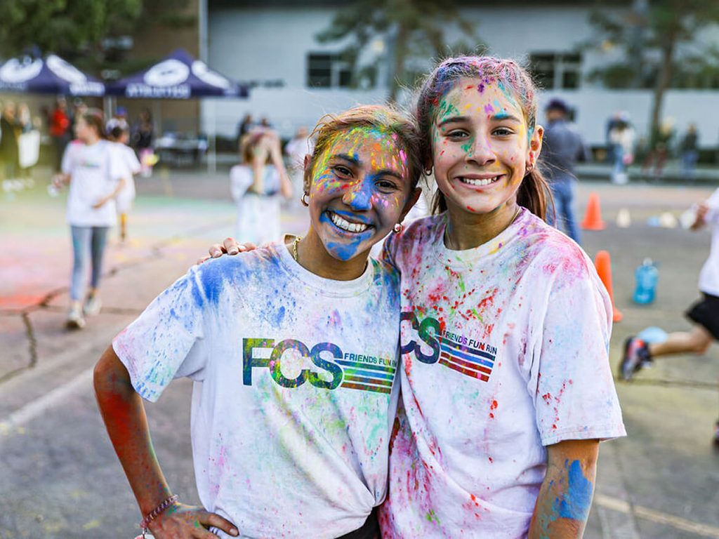 Two smiling students covered in colored powder at the FCS color run