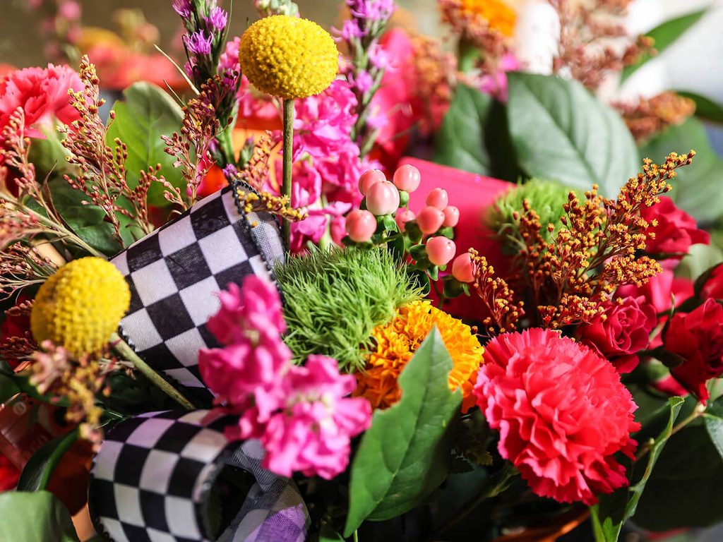 Colorful flower centerpiece with checkered racing flags at a school fundraiser