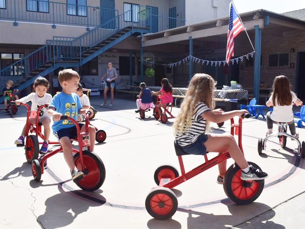 Young students riding tricycles on the school playground