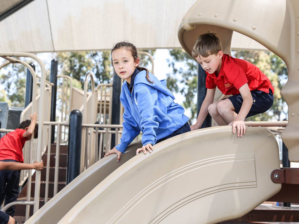 Two students climbing on the playground slide at Friends Christian School